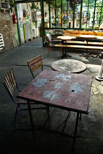 A vertical shot of two old cafe tables with two chairs in the daylight