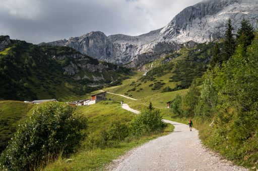 The Jubilaumsgrat Path on a vibrant green hill leading to the Zugspitze peak on a cloudy day
