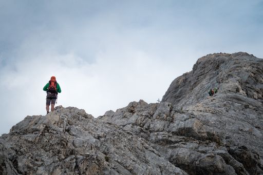 A tourist with a backpack standing at the edge of a cliff on Zugspitze, Germany/Austria