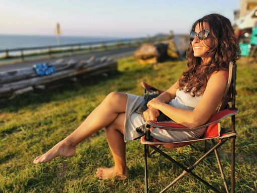 A shallow focus shot of a young woman sitting on a chair in front of a beach