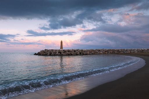 Summer landscape view of a lighthouse on a beachfront at sunset in Marbella Spain
