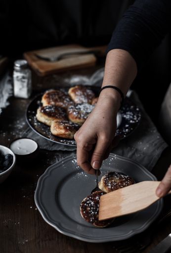 A vertical shot of hands arranging a delicious pastry decorated with powdered sugar on a plate