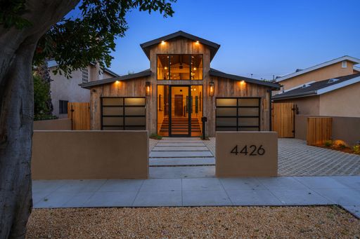 A modern house exterior, featuring a wooden facade and glass garage doors. Southern California
