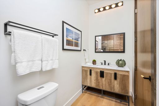 A modern bathroom interior with a wooden vanity, white towels, and framed artwork. Southern California
