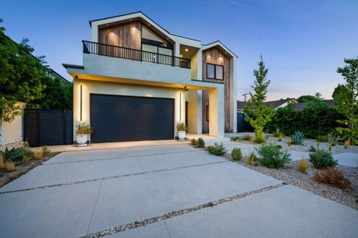 Modern two-story house with sleek design and landscaped front yard under a clear evening sky.