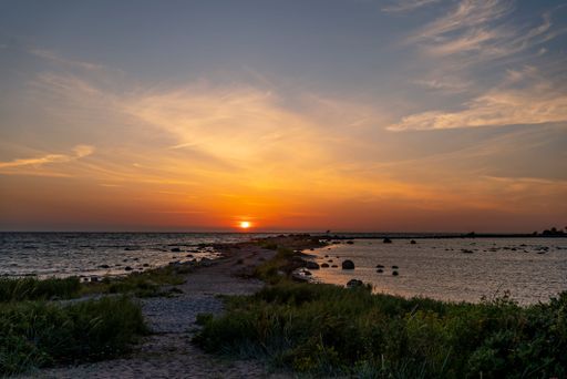 Serene sunset over a rocky coastline with gentle waves and a vibrant sky, capturing the beauty of nature's evening colors.