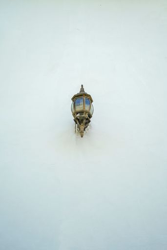 A vertical shot of a street light on a white building wall