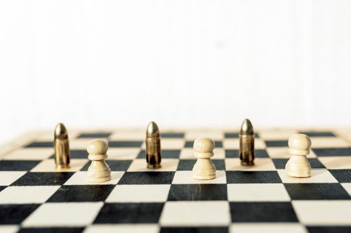 A selected focus shot of a chess board with figures of white pawns and golden bullets