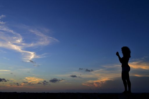 The silhouette of a person standing on the edge of a wall under the beautiful sky at daw