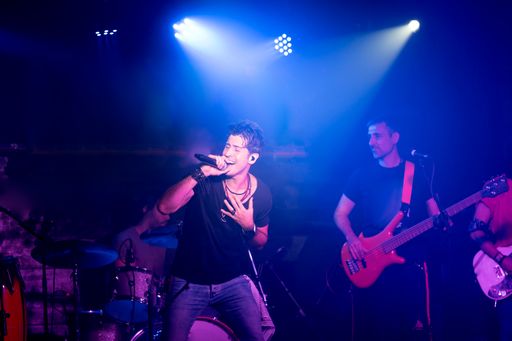 A rock band performing in a club surrounded by blue led lights