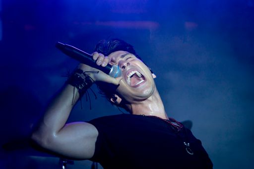 A young energetic singer performing in a club under blue led lights