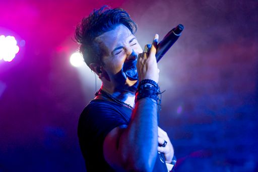 A young energetic singer performing in a club under colorful led lights