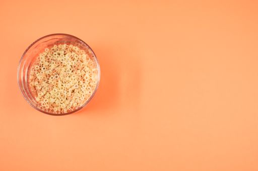 A jar of macaroni pasta on orange background with free space for text