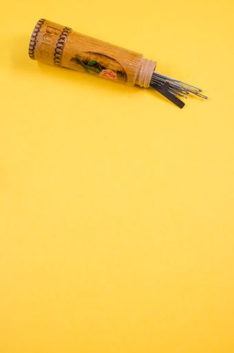 A wooden bottle holder of needles isolated on a yellow background with free space for text