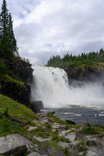 A scenic view of a river flowing through a green landscape in Taennforsen, Sweden on a cloudy day