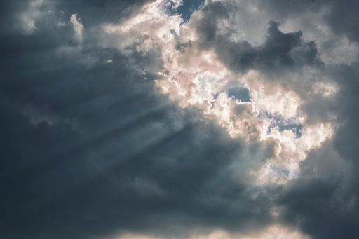 A piece of sunlight coming out from a small open space between the dark cloud
