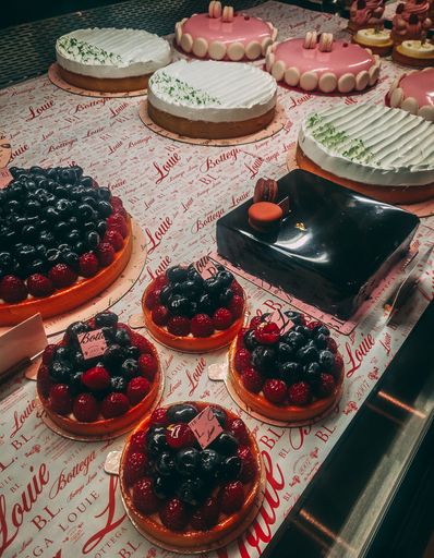 A vertical shot of various types of desserts including berry tarts and cakes on a table