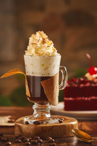 A vertical shot of a mochaccino with whipped cream topping arranged on a wooden surface