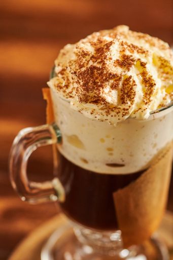 A vertical shot of a mochaccino with whipped cream topping arranged on a wooden surface