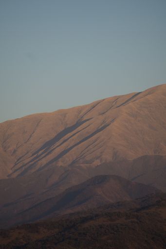 A vertical shot of brown hills on the background of blue sky.