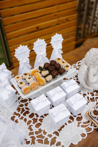 Elegant dessert table with assorted sweets and decorative boxes on a lace tablecloth, ideal for celebrations or weddings.