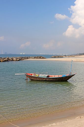 Small traditional Asian wooden fishing boat in a bay by the shore, southeast Asia
