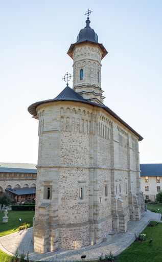 Historic stone church with ornate architecture and a tall domed tower, set against a clear blue sky in a serene setting.