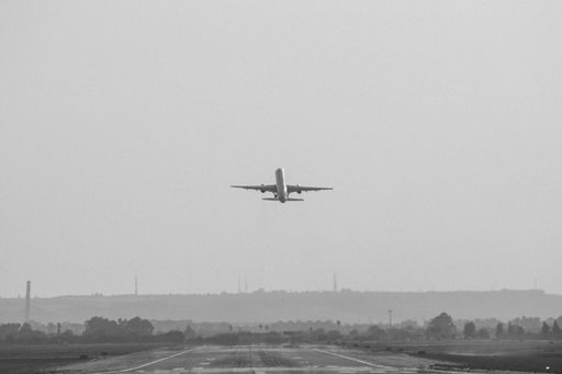 A grayscale shot of an airplane taking off from the airport