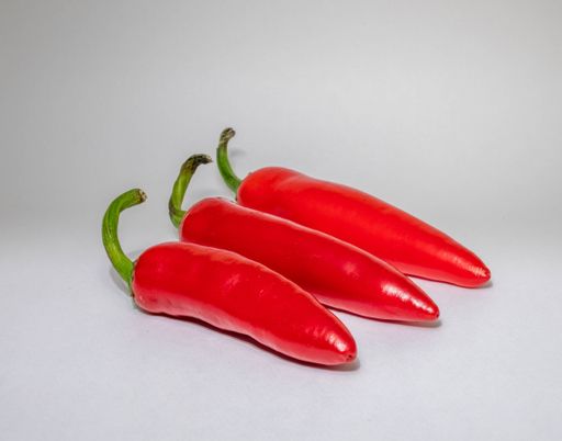 A closeup shot of three red chili peppers on white background