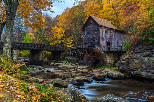 An old wooden mill by a stream in autumn, surrounded by colorful foliage. Babcock State Park, WV