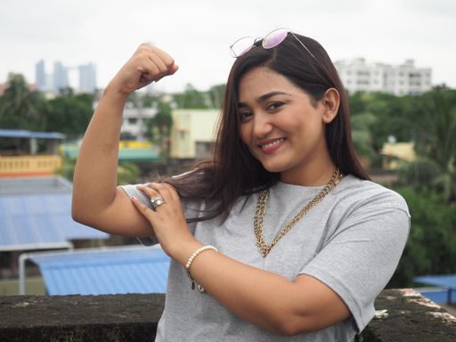 A closeup shot of a young South Asian female showing off her biceps comedy look