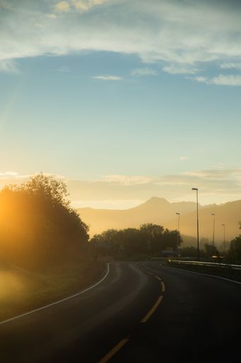 A sunset over a winding road with mountains in the background