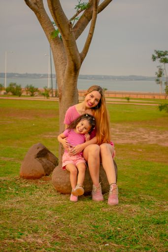 A mom and daughter dressed alike in an outdoor park playing with each other