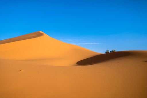A beautiful shot of sand dunes with a clear blue sky in the background at daytime