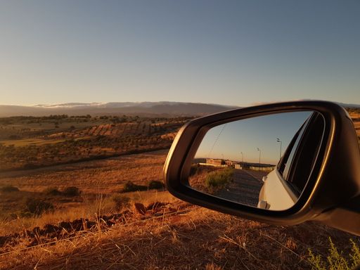 A closeup shot of a car wing mirror in a deserted countryside at sunset