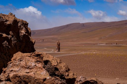 Desert landscape with rock formations under a partly cloudy sky in the Atacama Desert, Chile.