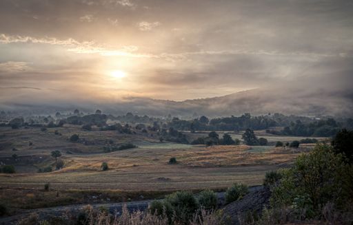 A cloudy sky partially covering the sun over a Croatian landscape