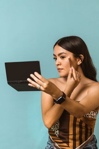 A portrait of a young attractive Caucasian female using a brush to do her makeup