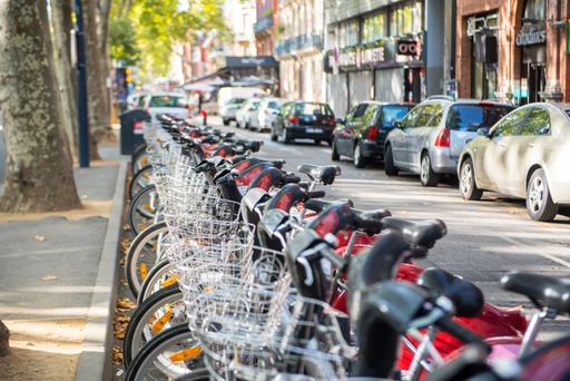 A row of bicycles and cars in a street