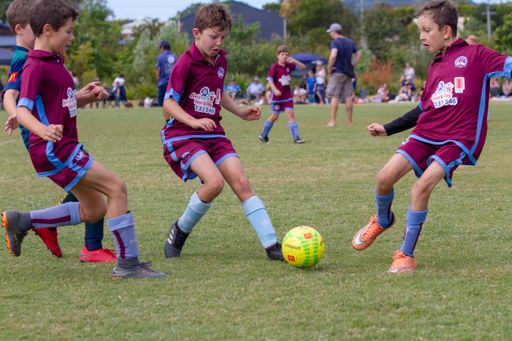 A group of children playing soccer on a field in Coolum Beach, Australia