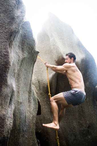 A vertical shot of an athletic Hispanic man doing rock climbing