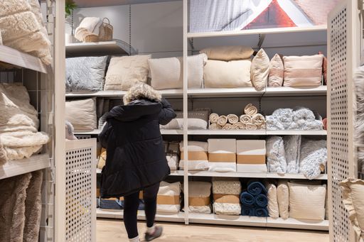 Woman buying in a home textile store, looking at pillows and blankets