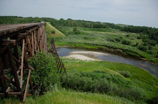 A  summer day in the countryside with a wooden bridge over a narrow river surrounded by a lush forest