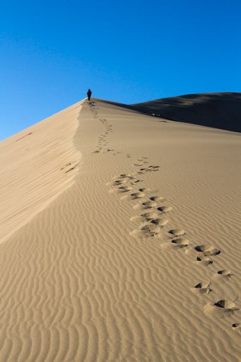 A person climbing a singing dune in the national park of Kazakhstan