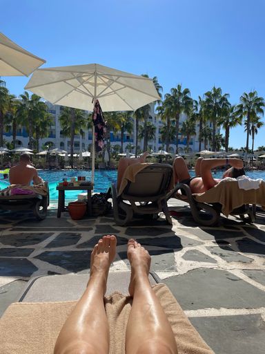 A group of people lying on pool beds in the pool inside a resort on a sunny day