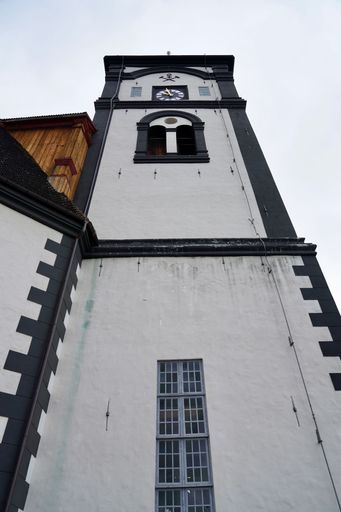 Low angle view of a historic clock tower with a distinctive black and white facade against a cloudy sky.