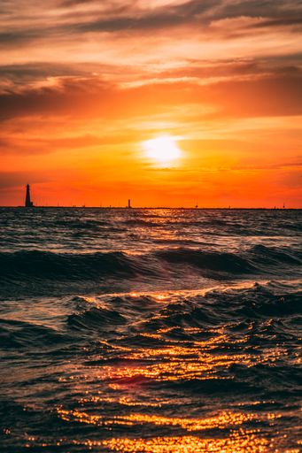 A vertical view of beautiful bright sunset sun reflected on wavy ocean