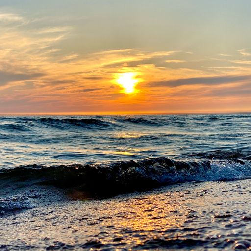 A vertical view of beautiful bright sunset sun reflected on a wavy ocean