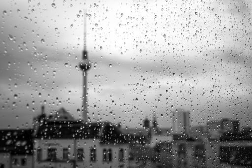 A closeup shot of water drops on a window with a blurred city in the background