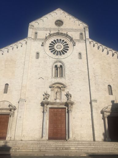 The facade of the Bari Cathedral in Italy, showcasing Romanesque architecture under a clear blue sky